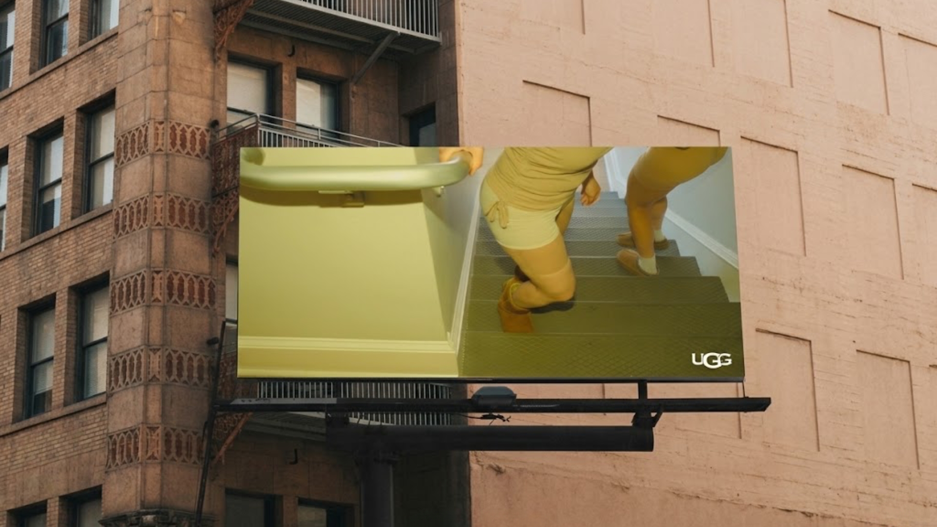 UGG OOH billboard — a figure in head-to-toe yellow climbing a staircase